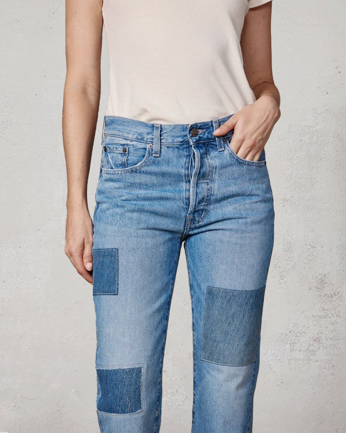 Person wearing blue patchwork jeans against a plain background