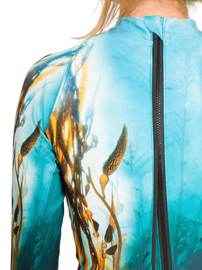 Close-up of the back shoulder of a sun suit with a zipper and a nature-themed kelp forest design on a plain background