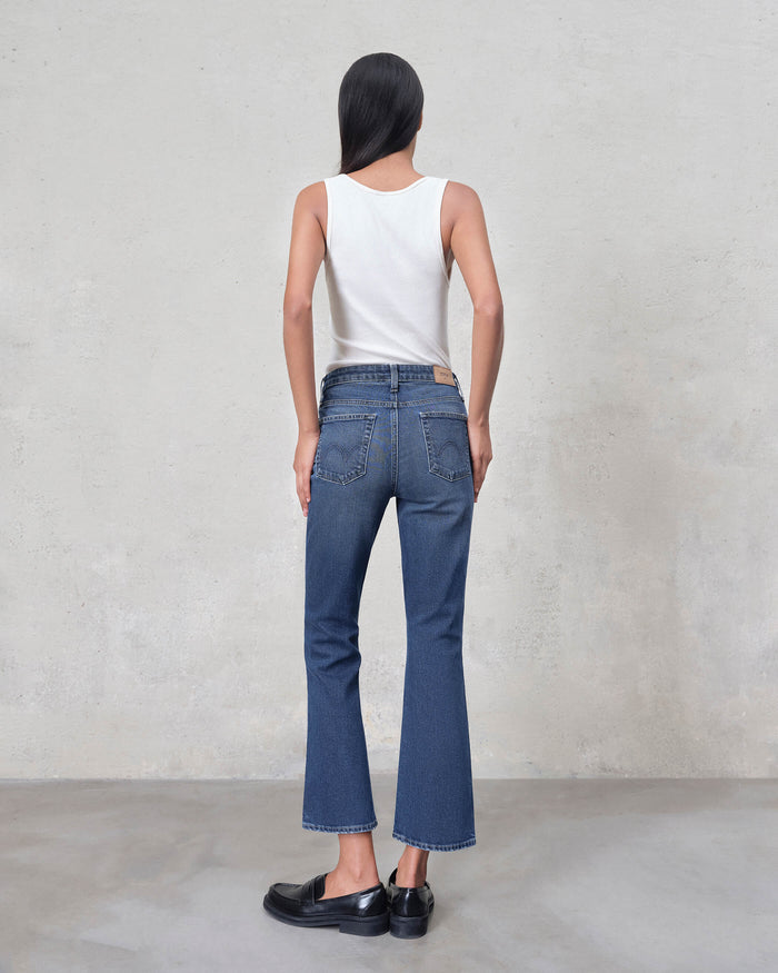 EDWIN women blue high rise cropped flared jeans back view on model with white tank and black loafers
