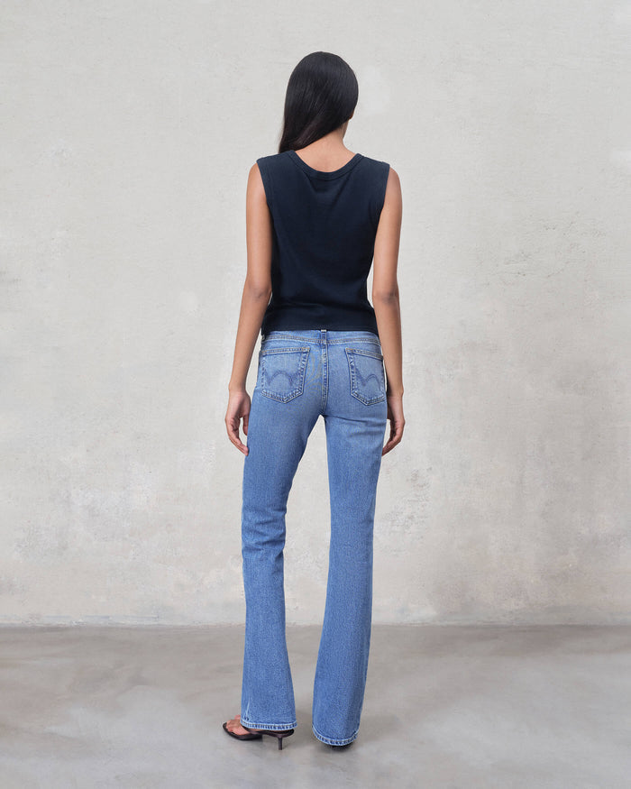 Person wearing blue jeans and a black sleeveless top against a plain background