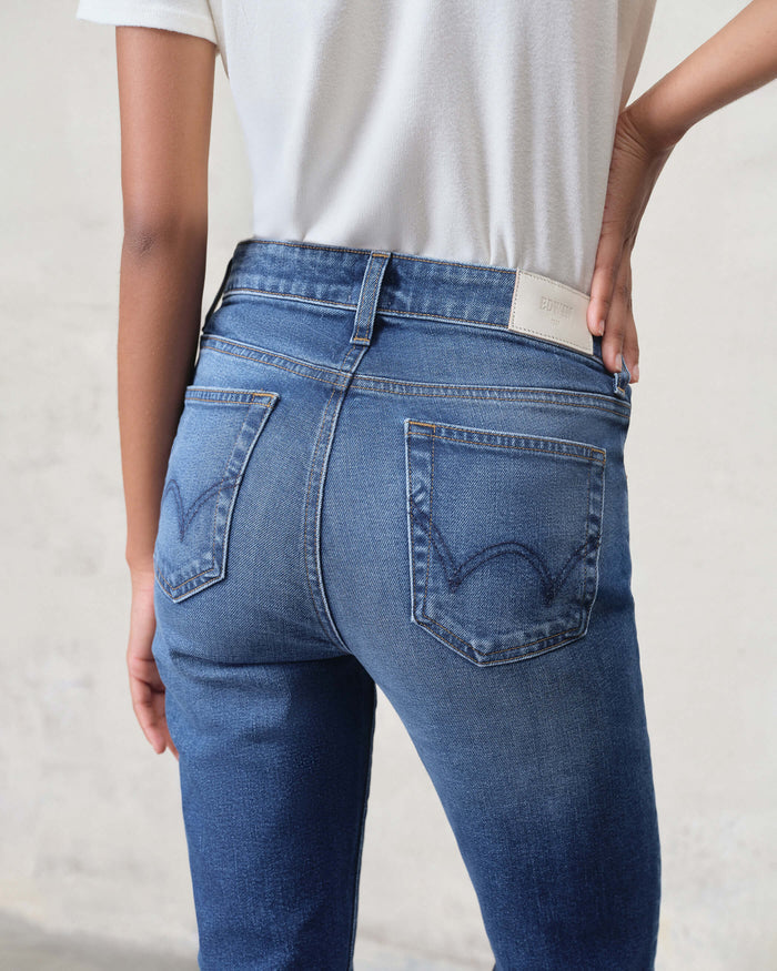 Back view of model wearing EDWIN women's bootcut jeans made in USA in medium blue wash with stitched back pockets