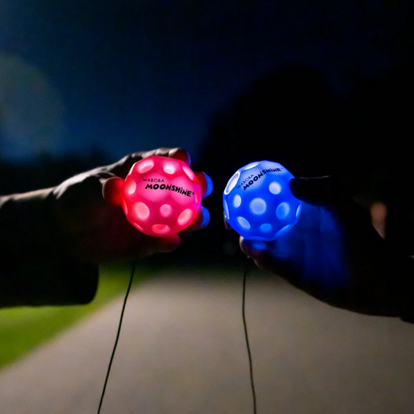 Red and Blue LED moon balls held in hands in dark