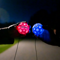 Red and Blue LED moon balls held in hands in dark