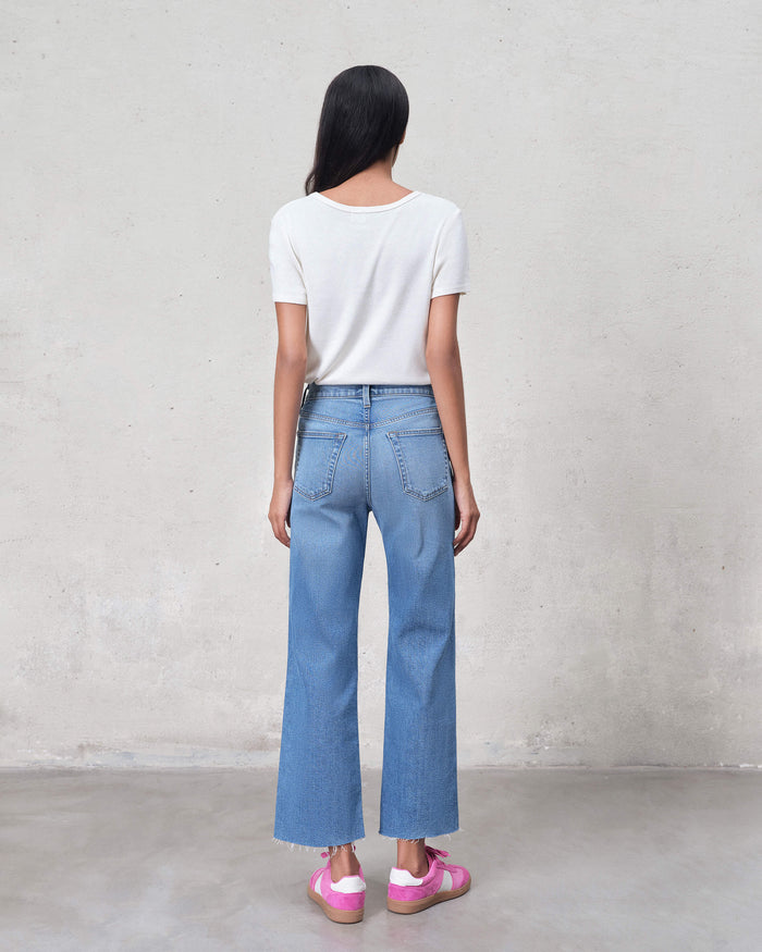 EDWIN back view of model wearing women's premium cropped wide leg jeans light wash with white tee and pink sneakers
