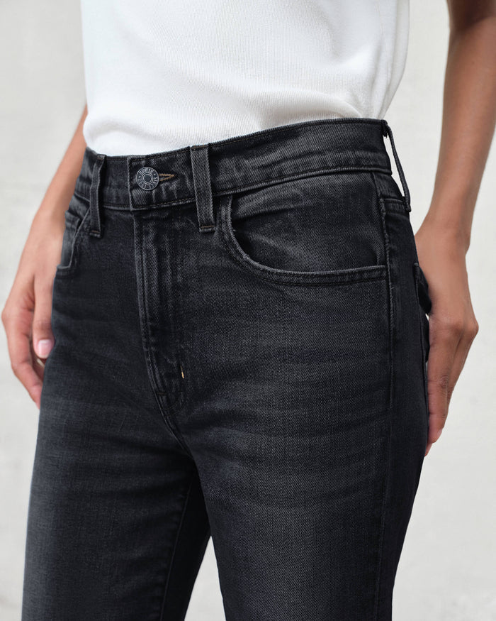 Person wearing black jeans and a white shirt against a plain background