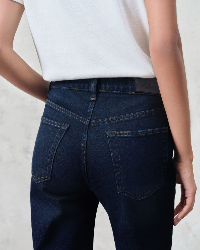 Person wearing dark blue jeans with a white background