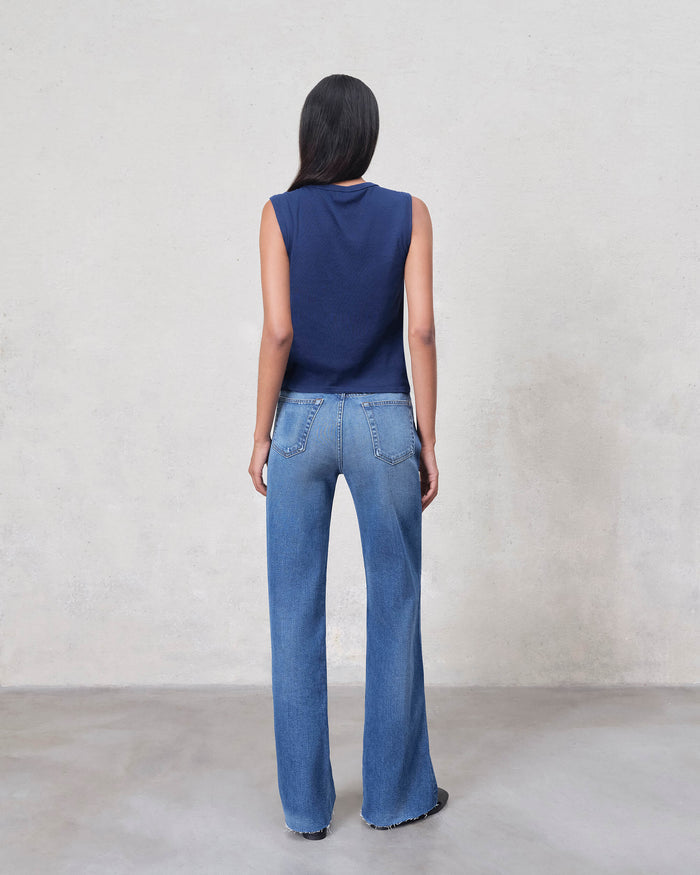 Rear view of EDWIN model wearing blue sleeveless top and wide leg raw hem jeans for women in medium wash
