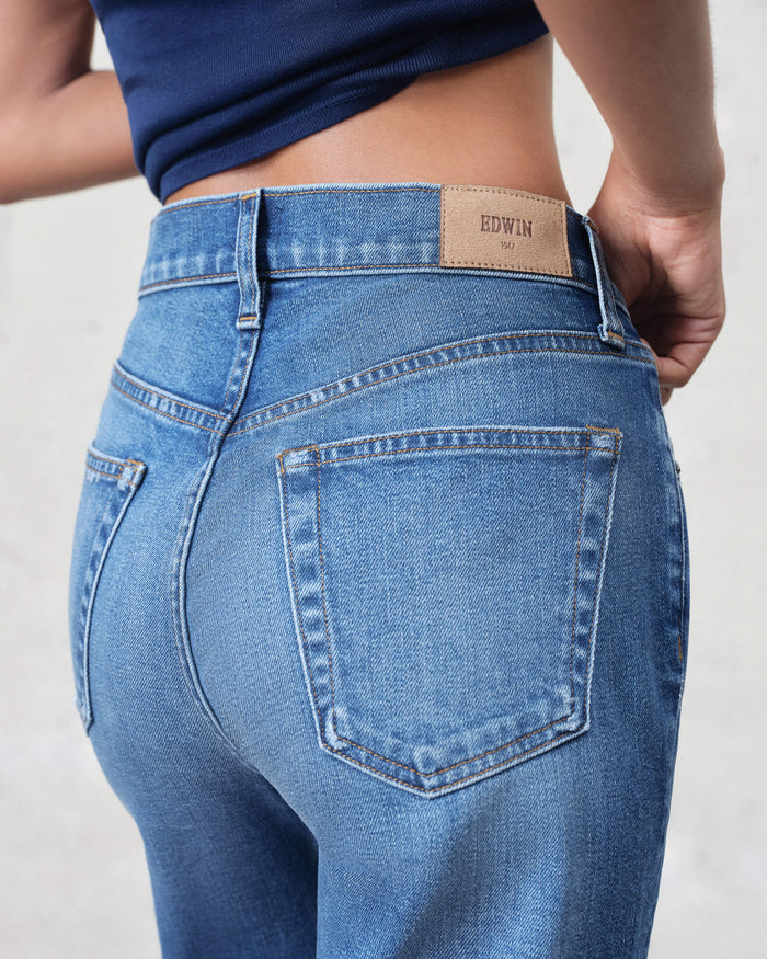 EDWIN medium blue denim wide leg raw hem jeans for women shown from back with rear pockets and leather patch