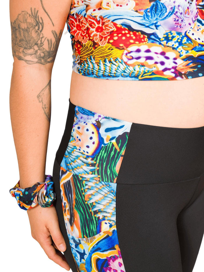 Close up of a bright colorful nudibranch print along the side of the leg of a black legging.
