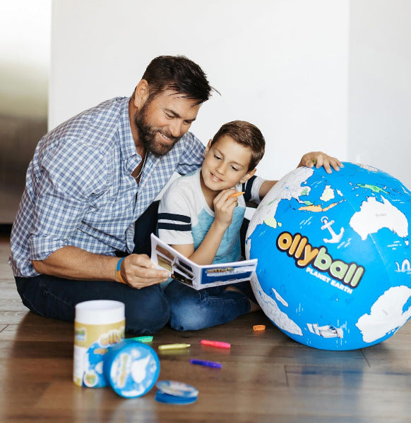 Man and child playing with an ollyball toy on a wooden floor.