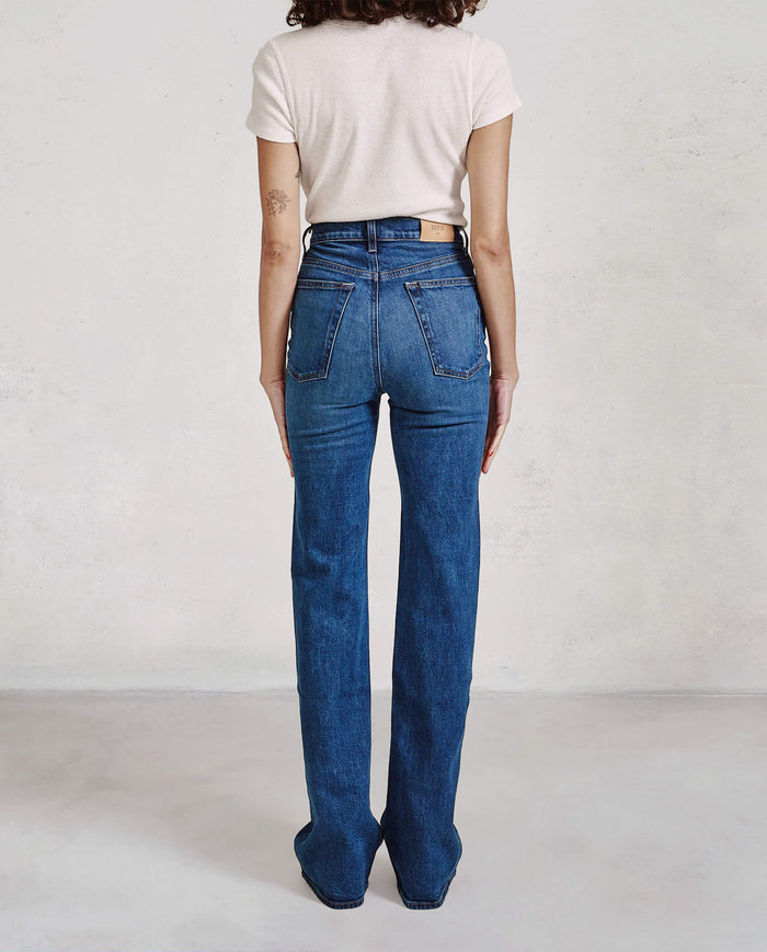 Person wearing blue jeans and a light-colored top against a plain background