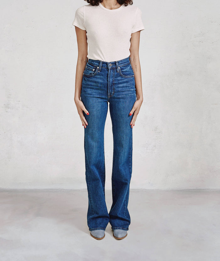 Person wearing blue jeans and a white shirt on a plain background