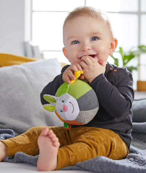 Baby holding a soft toy in a cozy living room