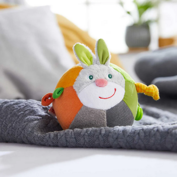 Plush toy with a rabbit design on a blanket in a home setting